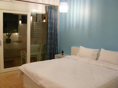 a bedroom with a white bed and a sliding glass door at Clear House Phuket in Kamala Beach