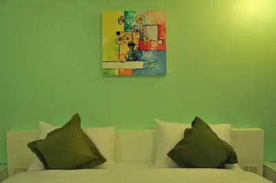 a bedroom with a bed with a painting on the wall at Clear House Phuket in Kamala Beach