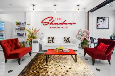 a living room with a white couch and red chairs at The Shades Hotel 50 meter Beach Front in Patong Beach