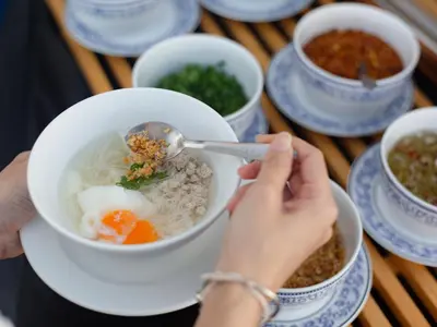 a person eating a bowl of soup with a spoon at Royal Phuket City Hotel in Phuket Town
