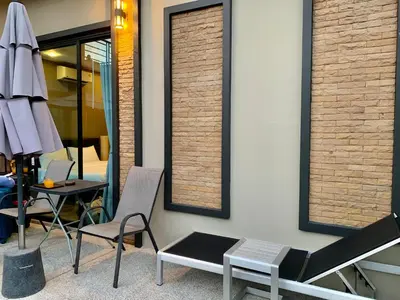 a room with two chairs and a table with an umbrella at Baan Fran Sim Da in Bang Tao Beach