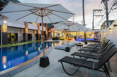 a row of chairs with umbrellas next to a pool at ETK Patong Resort in Patong Beach