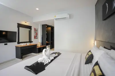 a bedroom with a large white bed with a mirror at ETK Patong Resort in Patong Beach