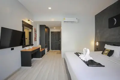 a hotel room with two beds and a television at ETK Patong Resort in Patong Beach