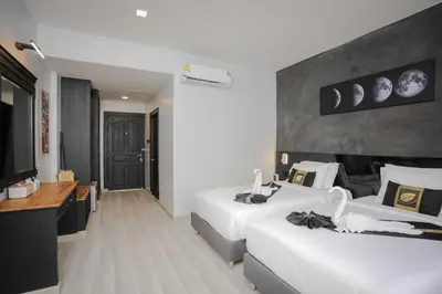a hotel room with two beds and a television at ETK Patong Resort in Patong Beach