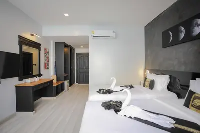 a hotel room with two beds and a television at ETK Patong Resort in Patong Beach
