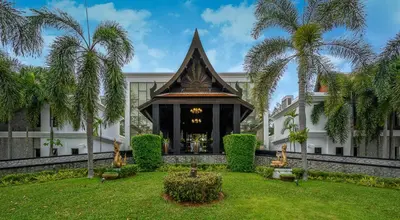 a building with palm trees in front of it at Maikhao Dream Villa Resort and Spa, Maikhao Phuket in Mai Khao Beach