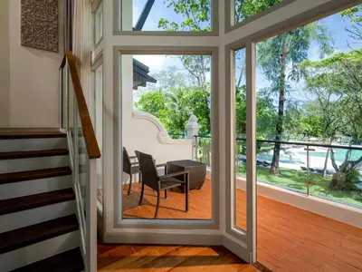 a glass door leading to a balcony with a table and chairs at Natai Beach Resort in Natai Beach