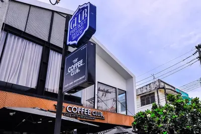 a coffee shop sign on a pole in front of a building at Glur Phuket Patong Beach in Patong Beach
