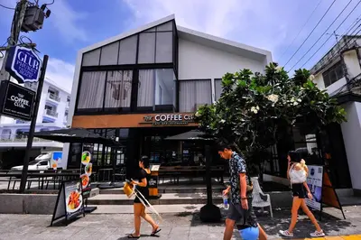 a group of people walking in front of a coffee shop at Glur Phuket Patong Beach in Patong Beach