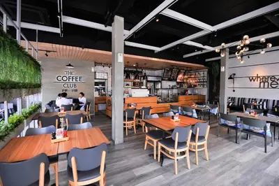 a restaurant with wooden tables and chairs and people eating at Glur Phuket Patong Beach in Patong Beach