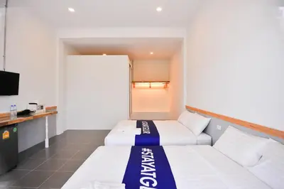 a hotel room with two beds and a tv at Glur Phuket Patong Beach in Patong Beach