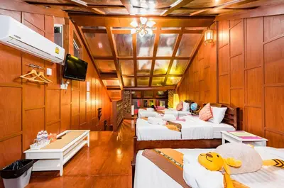 a room with four beds and a tv on a room at Baan Ratchapruek in Phuket Town