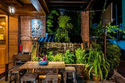 a dining room with a table and some plants at Baan Ratchapruek in Phuket Town