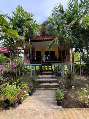a house with palm trees and flowers in front of it at Mookdaman Bungalow in Ko Yao Noi