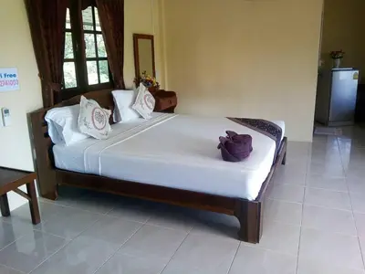 a bedroom with a bed with white sheets and a purple flower on it at Mookdaman Bungalow in Ko Yao Noi