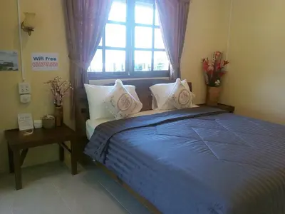 a bedroom with a blue bed with a window at Mookdaman Bungalow in Ko Yao Noi