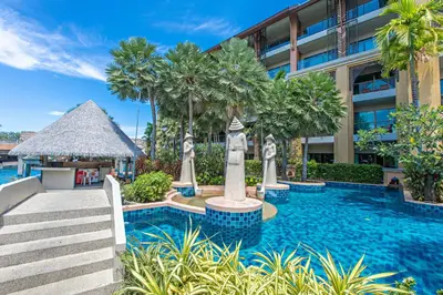 a resort swimming pool with statues in front of a building at Rawai Palm Beach Resort - SHA Extra Plus in Rawai Beach