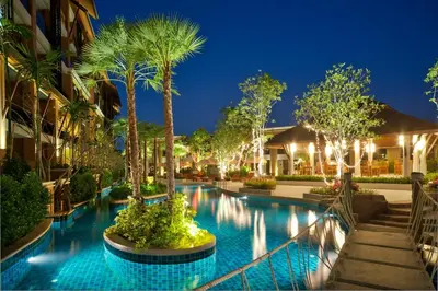 a resort swimming pool with palm trees and lights at Rawai Palm Beach Resort - SHA Extra Plus in Rawai Beach