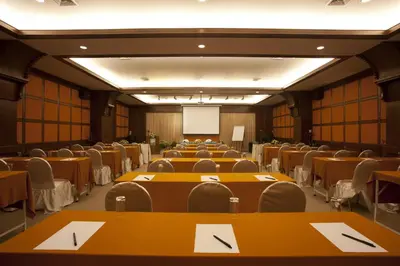 a conference room with tables and chairs and a screen at Rawai Palm Beach Resort - SHA Extra Plus in Rawai Beach