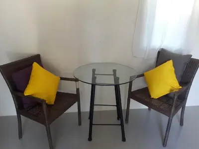 a glass table and two chairs with yellow pillows at Classic home in Bang Tao Beach