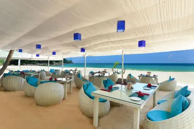 a restaurant on the beach with tables and chairs at Andaman White Beach Resort - SHA Plus in Nai Thon Beach