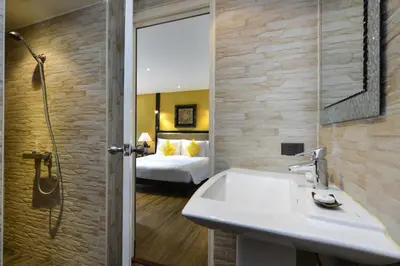 a bathroom with a sink and a bedroom at Andaman White Beach Resort - SHA Plus in Nai Thon Beach