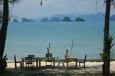 a table and chairs on a beach with the ocean at Koh Yao Beach Front in Ko Yao Yai