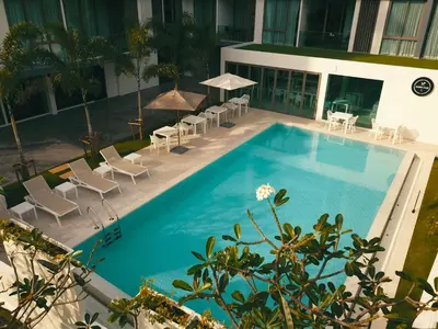 a swimming pool with chairs and tables and a building at Oceanstone by Holy Cow, 1-BR, next building view in Bang Tao Beach
