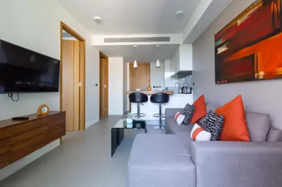 a living room with a gray couch with orange pillows at Oceanstone by Holy Cow, 1-BR, next building view in Bang Tao Beach