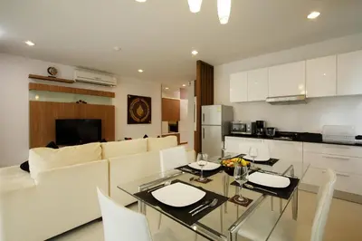 a kitchen and a living room with a glass table at The Park Surin Serviced Apartments by RESAVA in Surin Beach