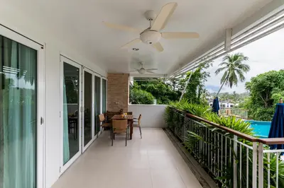 a balcony with a table and a ceiling fan at The Park Surin Serviced Apartments by RESAVA in Surin Beach