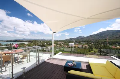 a balcony with a view of the water and mountains at The Park Surin Serviced Apartments by RESAVA in Surin Beach