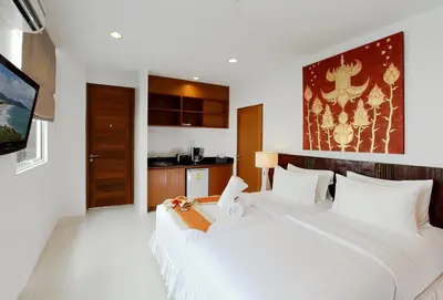 two white beds in a room with a tv at The Park Surin Serviced Apartments by RESAVA in Surin Beach