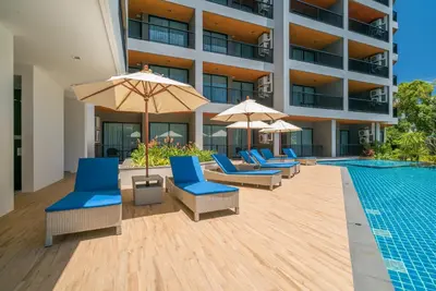 a pool with lounge chairs and umbrellas next to a building at Grand Kata VIP - Kata Beach in Kata Beach