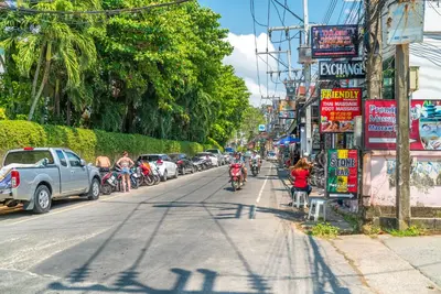 a street with parked cars and people riding bikes at Grand Kata VIP - Kata Beach in Kata Beach