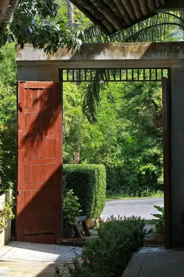 an open door to a garden with a bush at Tea Tree Boutique Resort in Rawai Beach