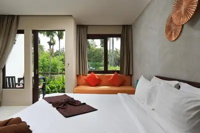 a bedroom with a bed and a couch and windows at Tea Tree Boutique Resort in Rawai Beach