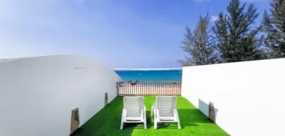 a row of chairs sitting on a lawn next to the ocean at Layalina Hotel in Kamala Beach