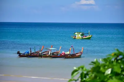 three boats in the water on a beach at Layalina Hotel in Kamala Beach