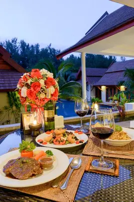 a table with plates of food and glasses of wine at L'esprit De Naiyang Beach Resort - SHA Extra Plus in Nai Yang Beach