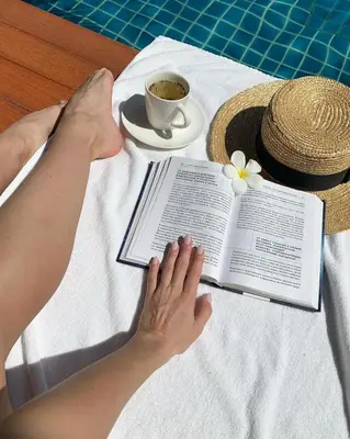 a person reading a book on a table with a cup of coffee at L'esprit De Naiyang Beach Resort - SHA Extra Plus in Nai Yang Beach