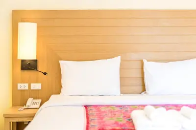 a bed with white pillows and a wooden head board at Baan Suwantawe in Phuket Town