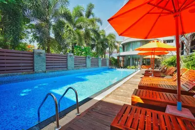 a pool with chairs and an umbrella next to a building at Baan Suwantawe in Phuket Town