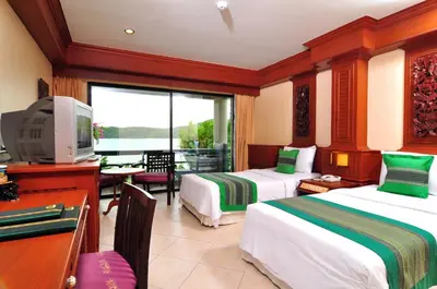 a hotel room with two beds and a desk and a television at Phi Phi Island Cabana Hotel in Phi Phi Don