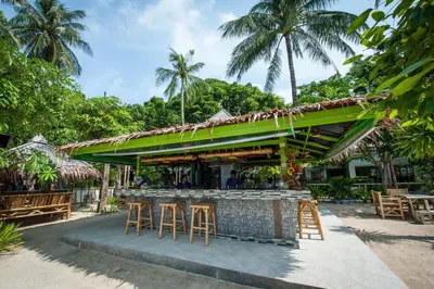a bar with a green roof and some stools at Phi Phi Island Cabana Hotel in Phi Phi Don