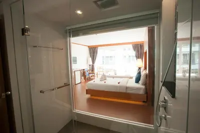 a bedroom with a bed and a glass door with a shower at Phi Phi Harbour View Hotel in Phi Phi Don