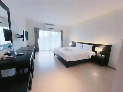 a bedroom with a bed and a dresser and a desk at Phuketa Hotel Phuket Town in Phuket Town