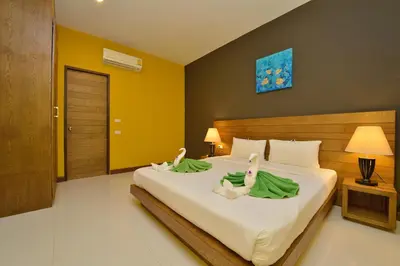 a bedroom with a bed with two swans on it at Happy Cottage in Chalong