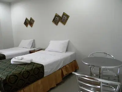 a room with two beds and a table and chairs at G&B Guesthouse in Patong Beach
